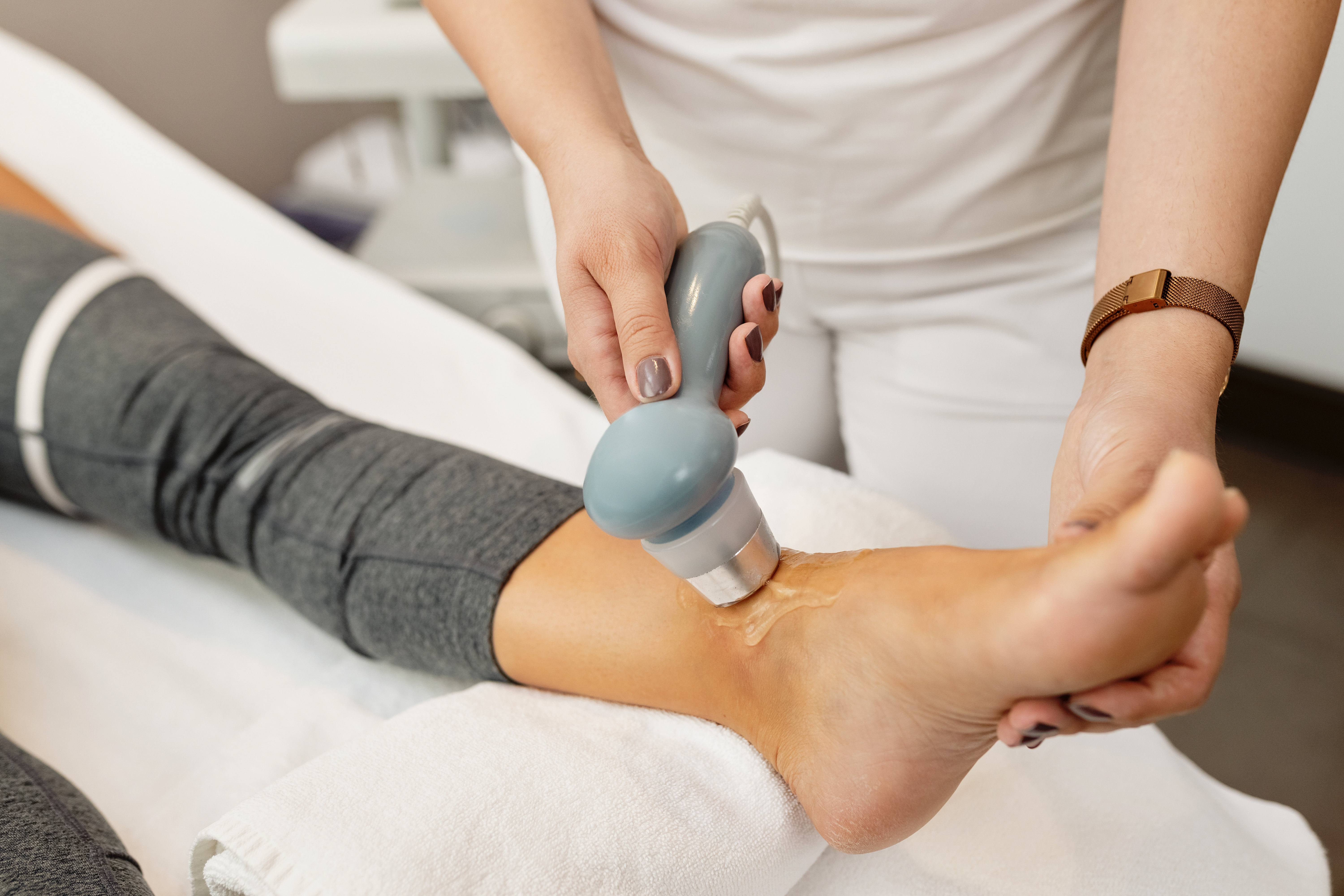 Physical therapist treating a client's joint with electrotherapy shockwave treatment